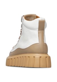 Sneaker alta bianca in pelle con superficie testurizzata, dettagli beige e suola in gomma beige spessa. Presenta una chiusura con zip e lacci decorativi.