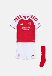 Ensemble de football pour jeunes rouge et blanc comprenant un maillot à manches courtes avec un motif texturé, un short blanc et une chaussette rouge avec des accents blancs.
