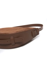 Brązowa torba na ramię z skóry i zamszu o zakrzywionym kształcie, gładkiej fakturze, regulowanym pasku i klamrze po boku.