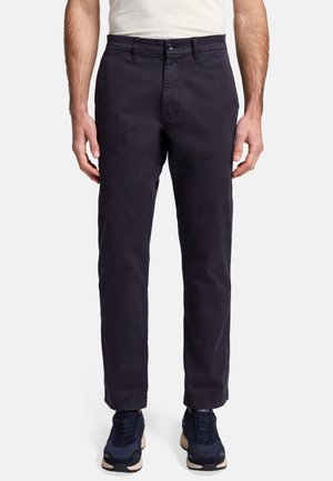Pantaloni navy in cotone, con vestibilità dritta, tasche frontali e chiusura con bottone, abbinati a sneakers scure.