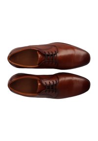 Chaussures habillées en cuir brun avec une finition lisse, un bout rond et des lacets. Présentent des détails texturés sur les côtés.