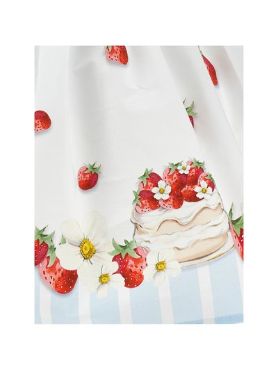 Λευκό ύφασμα με εκτυπωμένες φράουλες, λευκά λουλούδια και ένα στρωμένο κέικ με φράουλα στην κορυφή, πάνω σε ένα φόντο με μπλε και λευκές ρίγες.