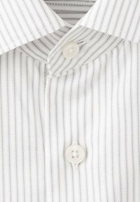 Camisa de rayas blancas en primer plano, con un cierre de botones. La tela presenta finas rayas en un tono claro y una textura suave.