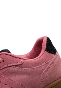 Sneaker in suede rosa con un accent in pelle nera texturizzata sul tallone, punta tonda e design con lacci. Presenta cuciture lungo i pannelli laterali.