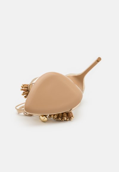 Scarpa con tacco alto beige, punta affilata, dettagli dorati e perline di legno decorative sulla cinghia, con una finitura lucida.