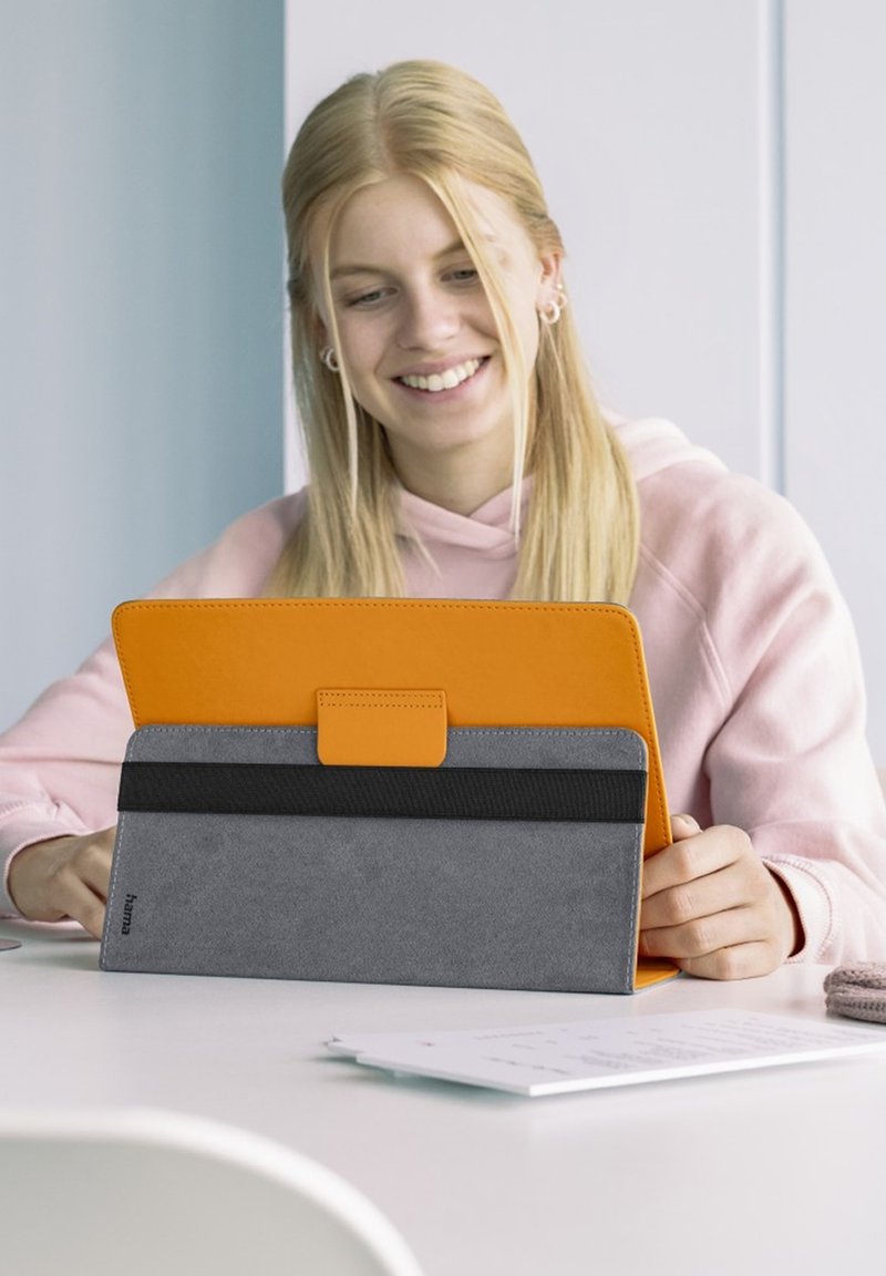 Tablettasche aus orangefarbenem und grauem synthetischem Material, mit einem faltbaren Design und einer strukturierten Oberfläche sowie einem schwarzen Akzentband.