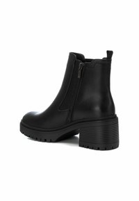 Botines negros de tobillo hechos de cuero suave, con una cremallera lateral, un tacón robusto y una suela de goma texturizada para mayor agarre.
