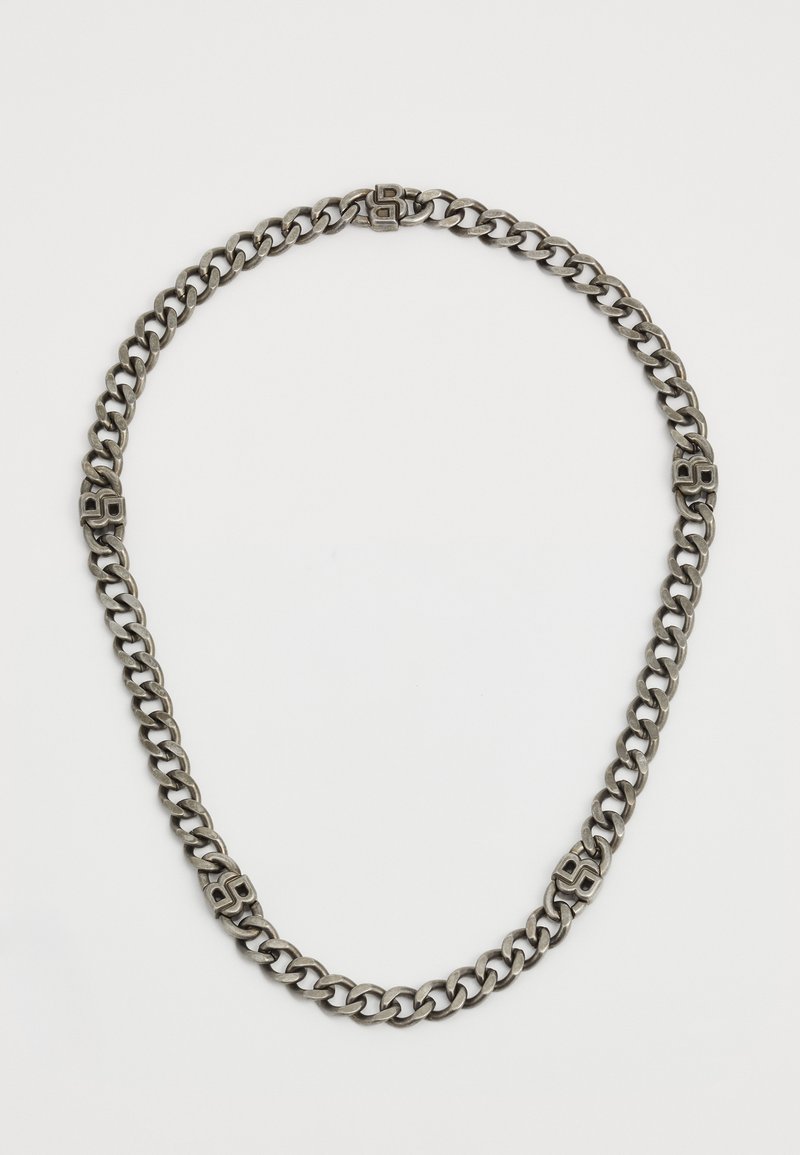 Zilverkleurige metalen ketting met grote schakels, voorzien van een gegraveerd detail in het midden. Glad van textuur, cirkelvormig van vorm.