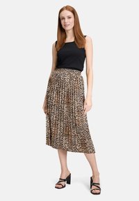 Czarny top bez rękawów z plisowaną midi spódnicą w panterkę w odcieniach beżu i brązu, zestawiony z czarnymi sandałami na słupku.