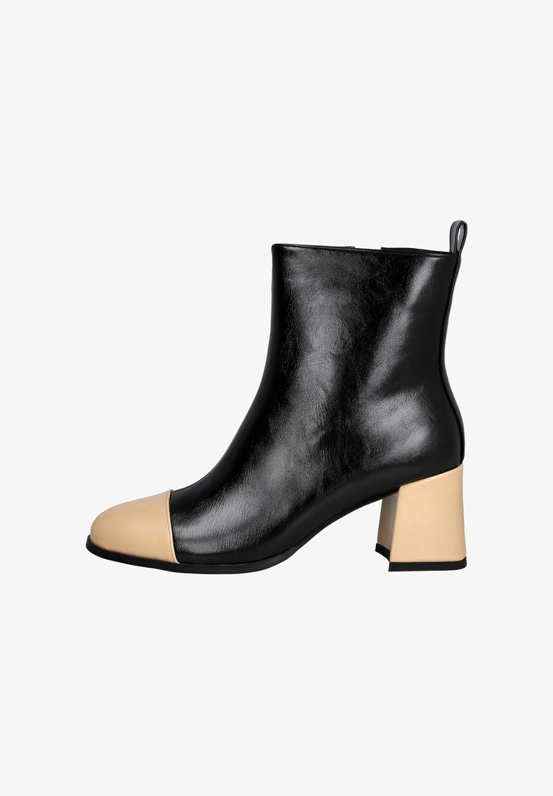 Botín negro de cuero hasta el tobillo con puntera beige. Presenta un tacón grueso y una textura suave. Sin hardware o acentos visibles.