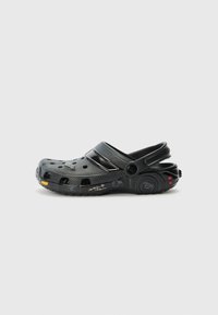 Black rubber clog with ventilation holes, back strap, textured surface, and yellow and red accents on the sole. Lightweight design.