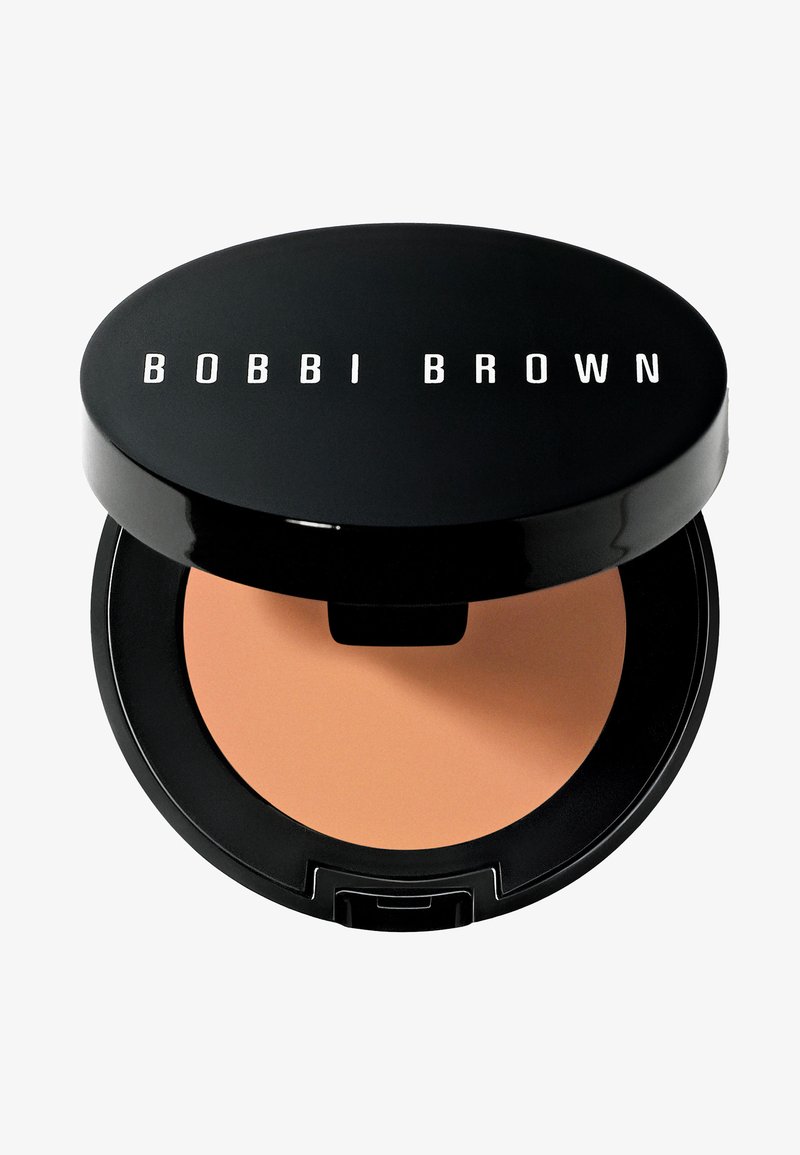 Poudre compacte de Bobbi Brown dans un étui noir brillant. Présente une teinte de poudre beige lisse avec une forme ronde et un logo clair sur le dessus.