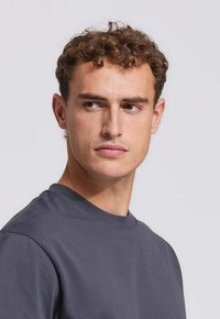 Grijze T-shirt met korte mouwen en een ronde hals, gemaakt van soepel stof. De pasvorm is casual, met zichtbare stiksels op de halslijn.