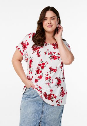 Bela cvetlična bluzica z rdečimi cvetovi, okroglo izrezana, kratki rokavi in sproščen kroj. V kombinaciji z svetlo modrim jeans krilom.