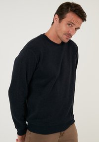 Tengerészeti crewneck pulóver, puha anyagból készült, hosszú ujjakkal, bordás mandzsettákkal és szegéllyel. A fazon laza illeszkedésű, látható logók nélküli.