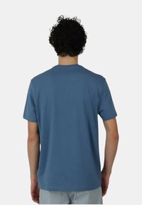 T-shirt blu a maniche corte con collo tondo e una texture liscia. Presenta un design semplice senza loghi o motivi visibili.