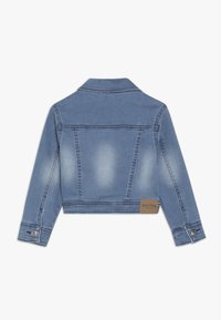 Giacca di denim azzurra chiara, di lunghezza cropped, con due cuciture posteriori, colletto classico, bottoni metallici ai polsini e un'etichetta tessuta all'orlo.