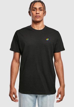 Svart bomull T-shirt med en liten livlig regnbågs-hjärta logotyp på vänster bröstområde, korta ärmar och en klassisk rundhalsad design.