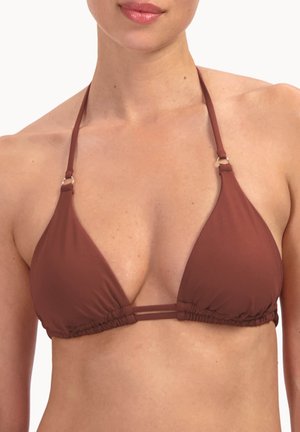 Femme portant un haut de bikini marron à col licou avec des bretelles fines et des détails en anneaux métalliques, visible des épaules jusqu'au milieu du torse.