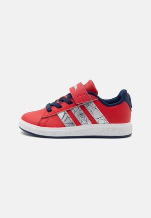 Rode en marineblauwe kindersneaker met witte strepen met spinnenwebpatroon, marineblauwe veters en een klittenbandsluiting op een witte zool met subtiele webpatronen.