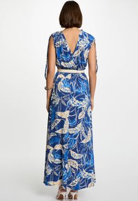 Robe longue bleu à motifs floraux avec un dos en V, des manches chauve-souris et une ceinture contrastante à la taille. Le tissu a une texture lisse et des motifs audacieux.