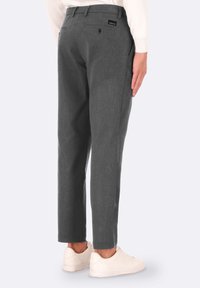 Pantaloni grigi a righe sottili realizzati in un tessuto testurizzato, dotati di due tasche posteriori e una vestibilità slim. Indossati con sneakers bianche.