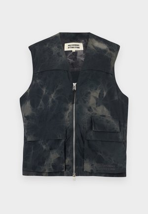 Czarna i szara kamizelka tie-dye z zamkiem błyskawicznym z przodu, dwoma kieszeniami z patkami oraz metką "AIGLE EXPERIENCE BY ÉTUDES STUDIO" wewnątrz kołnierza.