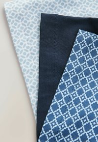 Tres piezas de tela: una azul clara con un patrón circular, una azul oscura sólida y una azul estampada con diseños geométricos, todas con bordes bien terminados.