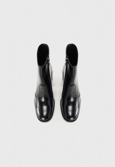 Svarta läderankelboots med en slät finish, utrustade med en sidovdragkedja och en rund tå. Designen är strukturerad med en minimalistisk siluett.