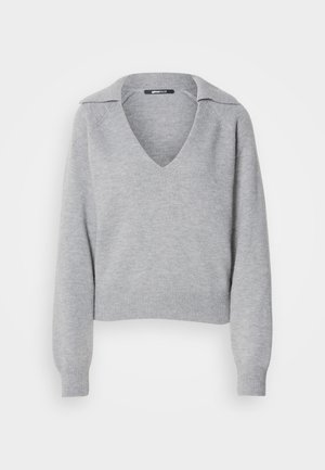 Pelēks adīts džemperis ar V-veida kaklu un apkakli, ar garām piedurknēm un ribotām aprocēm. Mīksta tekstūra, nogriezts dizains, minimālas detaļas.