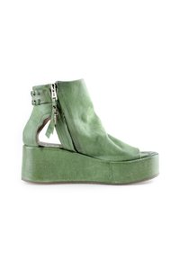 Sandale plateforme en cuir vert avec fermeture éclair, talon découpé, bride de cheville avec œillets en métal et design à bout ouvert.