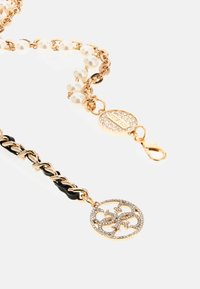 Chaîne ton or avec des perles de style perle et un accent noir. Présente un pendentif avec un design décoratif et des ornements en cristal.