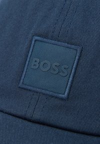 Dark blue fabric cap with a square patch displaying the raised text "BOSS" in matching blue tones.