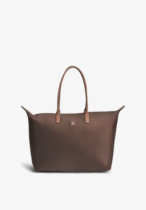 Sac cabas brun foncé avec deux fines poignées marron clair et un petit logo argenté au centre avant sur fond blanc.