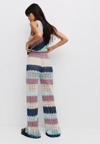 Gehaakt twee-delig set met een mouwloze top en broek met wijde pijpen. Bevat horizontale strepen in blauw, roze, crème en lavendel.