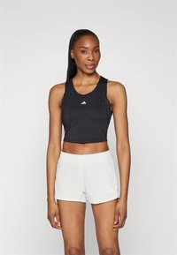 Schwarzes, kurz geschnittenes Sport-Top mit rundem Halsausschnitt und weißem Logo, kombiniert mit hellgrauen Shorts mit elastischem Bund und Logo.