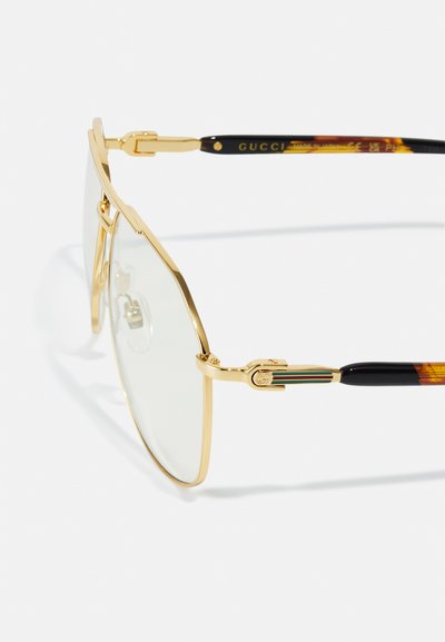 Gold metal frame sunglasses with clear lenses. Tortoiseshell-patterned temples feature a gold accent with green and red stripes.