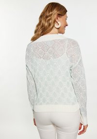 Pullover lavorato a maglia di un blu chiaro con un motivo a diamante testurizzato, orlo e polsini a coste di colore crema, con un design della schiena aperta.