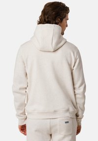 Felpa con cappuccio color beige chiaro realizzata in tessuto morbido, con tasca a marsupio e polsini a coste, vista da dietro.