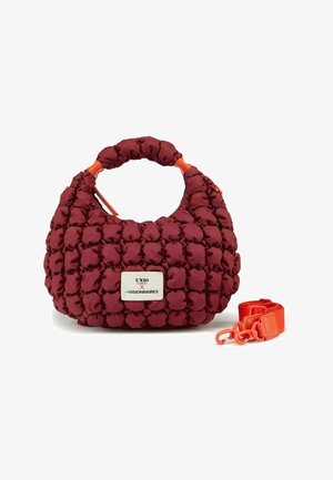 Sac à main matelassé bordeaux avec surface texturée, poignée courte et bandoulière orange amovible. Présente une plaque de marque en argent.