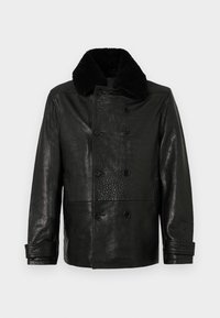 Veste en cuir noir avec une finition texturée, design croisé, six boutons et un col en fausse fourrure noire. Coupe régulière avec poches latérales.