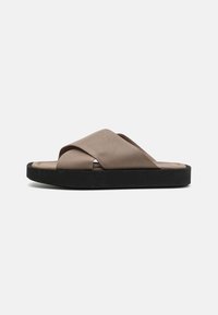 Brown leather slide sandals with a crisscross strap design and a textured upper. Black rubber sole provides contrast and durability.