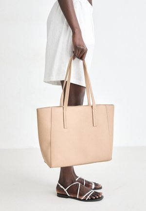 Beige leather tote bag with two long handles, rectangular shape, smooth texture, and minimalistic design.