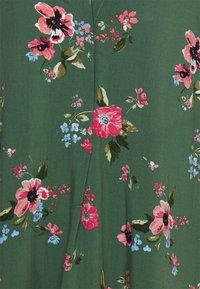 Abito floreale in tessuto verde scuro con fiori rosa, rossi e blu e foglie verdi, rifinito con un design frontale plissettato.