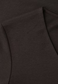 Nærbillede af mørkebrunt stof med synlig søm og foldet kant, der fremhæver tekstur og syningsdetaljer.