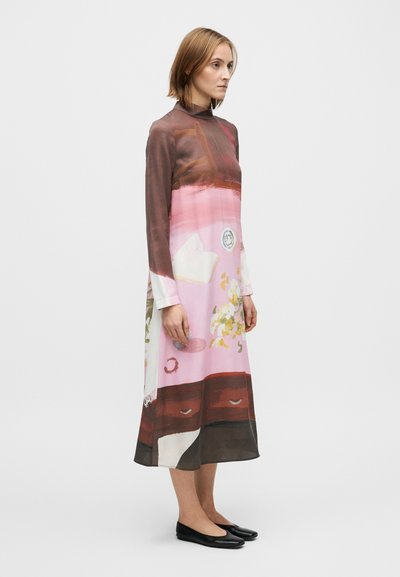 Suknelė iš lengvos medžiagos, derinanti rožinius, rudus ir gėlių raštus; ilgomis rankovėmis ir aukštu kaklu, atsipalaidavusio silueto.