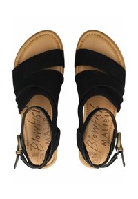 Černé semišové sandály se čtyřmi širokými popruhy, nastavitelným páskem kolem kotníku a hnědým stélkou. Mají hladký povrch a zaoblený tvar.