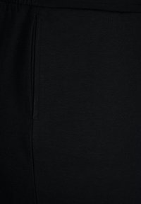 Černá bavlněná látka s hladkým povrchem, obsahující boční kapsu. Design je praktický s minimalistickým vzhledem.
