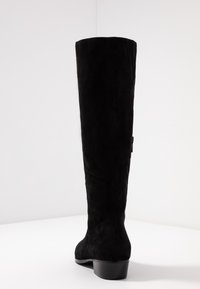 Czarne zamszowe kozaki za kolano z okrągłym noskiem i niskim słupkowym obcasem. Posiadają gładką teksturę i minimalistyczny design. Szew na plecach.