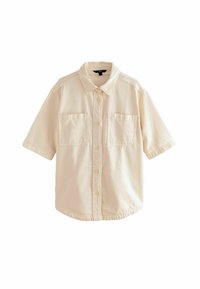 Chemise à manches courtes beige clair, avec un col, deux poches poitrine et une coupe décontractée. Le tissu semble doux et légèrement texturé.